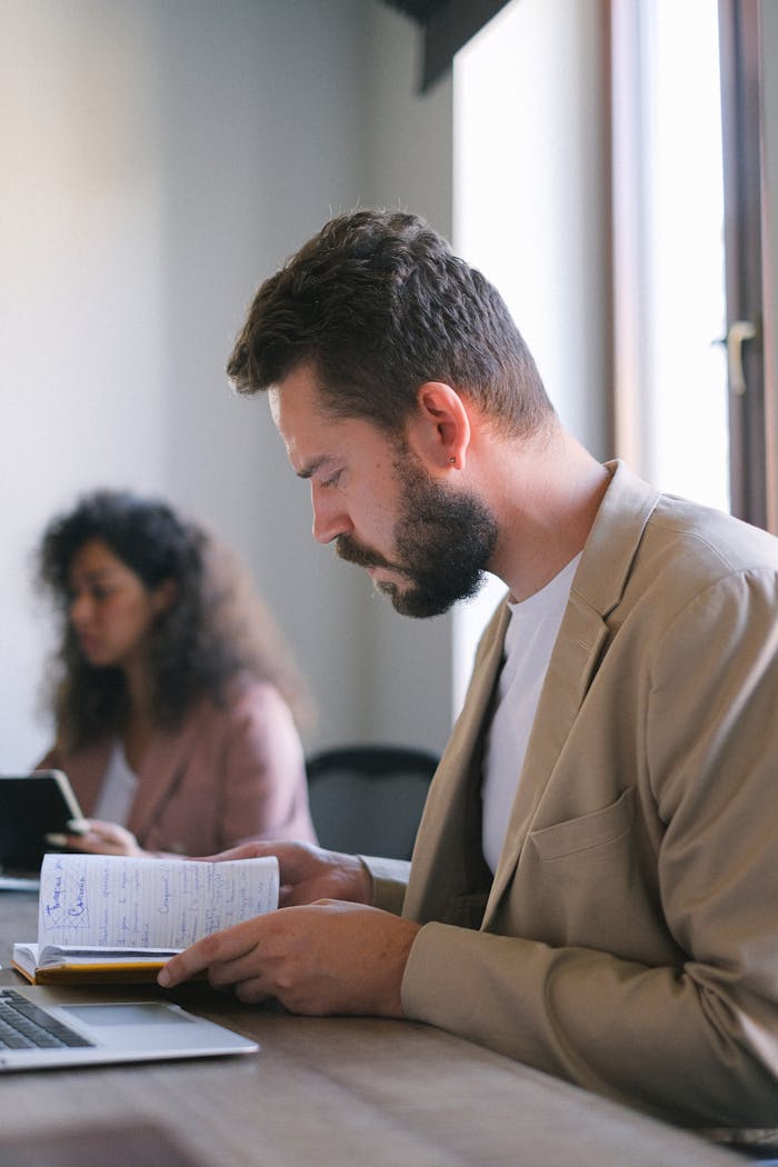 A man and woman deeply engaged in reading and working in an office setting.